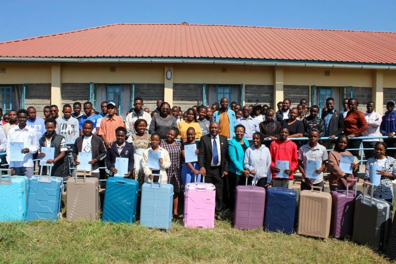 Programme graduates hold up their certificates outside a training centre